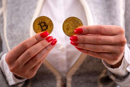 Virtual cryptocurrency money Bitcoin golden coins in the hands of a woman with red nail polish. The future of money.の写真素材