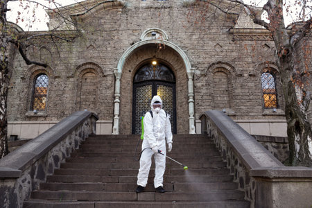 Sofia, Bulgaria - 11 April, 2020: Worker sprays disinfectant outside of Sveta Nedelya Church against the spread of coronavirus disease COVID-19.のeditorial素材