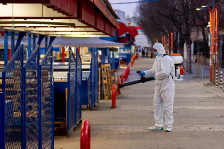 Sofia, Bulgaria - 7 April, 2020: Worker sprays disinfectant outside of ? food market against the spread of coronavirus disease COVID-19.のeditorial素材