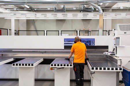 A worker works on woodworking machine in a factory. Wood and wood-based materials industry.の写真素材