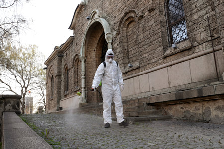 Sofia, Bulgaria - 11 April, 2020: Worker sprays disinfectant outside of Sveta Nedelya Church against the spread of coronavirus disease COVID-19.のeditorial素材
