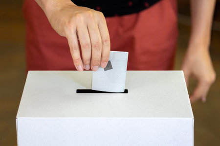 Person casts his vote into a ballot box during elections.の写真素材