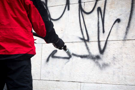 Worker cleans graffiti from a public building wall using pressure sand blaster.の写真素材
