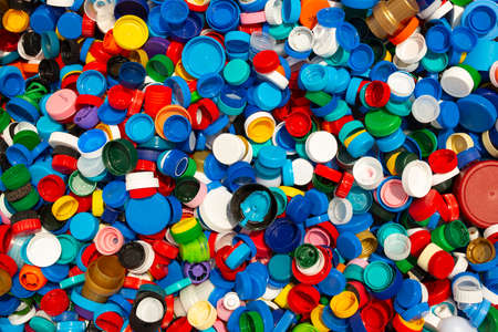 Thousands of different colourful plastic caps are seen stacked for recycling.の写真素材