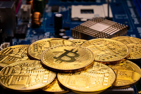Virtual cryptocurrency money Bitcoin golden coins on a computer printed circuit board PCB. The future of money. Computational equipment.の写真素材