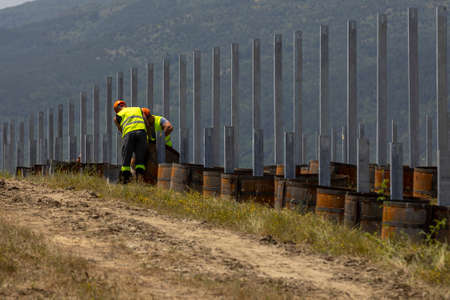 Workers construct a solar panels installation in a field.の写真素材