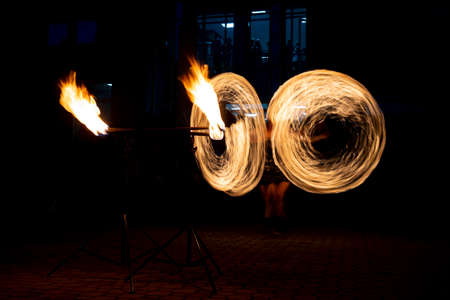 Young woman spins a torch during a fire show at night.の写真素材