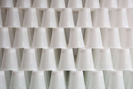 White plastic cups are seen stacked. Most disposable plastic utensils are made of polystyrene.の写真素材