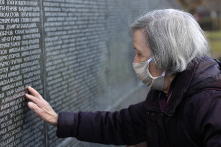 Sofia, Bulgaria - 1 February, 2021: A woman touches Victims of Communism Memorial monument inscribed with names of victims of the communist rule in Bulgaria. The country marks the Day of Remembrance and Respect to victims of the communist rule which endedのeditorial素材