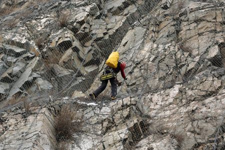 Sofia, Bulgaria - 31 January, 2021: Worker climbs the safety net near the aftermath of a stone landslide at the eighth kilometer of Struma Motorway.のeditorial素材