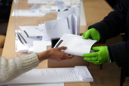 Sofia, Bulgaria: 4 April, 2021: Person with protective gloves receives her ballot at a polling...