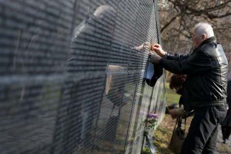 Sofia, Bulgaria - 1 February, 2021: A man touches Victims of Communism Memorial monument inscribed with names of victims of the communist rule in Bulgaria. The country marks the Day of Remembrance and Respect to victims of the communist rule which ended iのeditorial素材