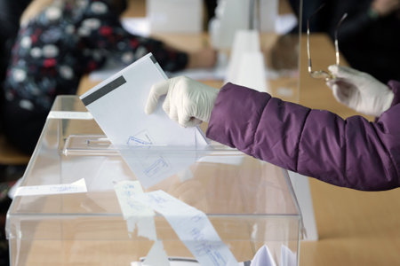 Sofia, Bulgaria: 4 April, 2021: Woman wearing protective gloves casts her ballot at a polling station for the parliamentary elections.のeditorial素材