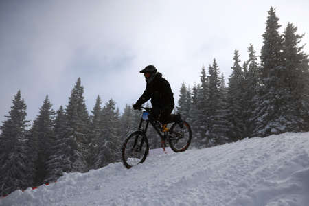 Cyclist rides a bike during an extreme snow downhill riding mountain bicycle competition,の写真素材