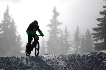 Cyclist rides a bike during an extreme snow downhill riding mountain bicycle competition,の写真素材