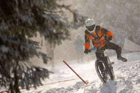 Cyclist rides a bike during an extreme snow downhill riding mountain bicycle competition,の写真素材