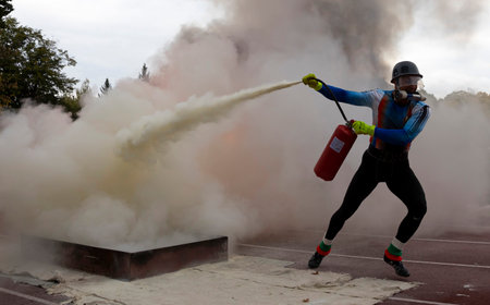 Sofia, Bulgaria - 13 October, 2021: Firefighter extinguishes fire with fire extinguisher during a training competition.のeditorial素材
