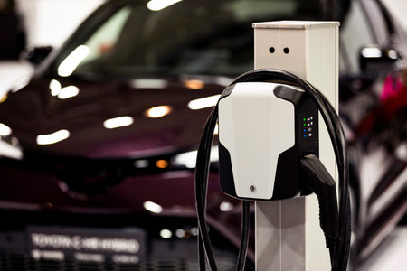 Electric car and an EV charging station. Electric vehicle at a charging station with the power cable supply seen at the charger station.の写真素材