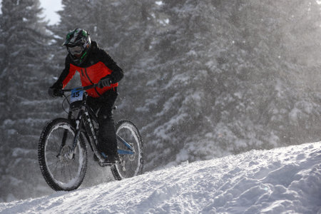 Sofia, Bulgaria - 22 January, 2022: Cyclist rides a bike downhill during an extreme snow riding mountain bicycle competition in Vitosha mountain.のeditorial素材