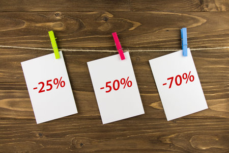 A piece of paper on a clothespin on a wooden background. Discounted price