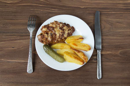 Grilled meat with potato and cucumbers on a wooden background. Close upの写真素材