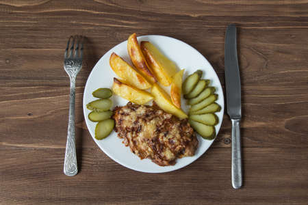 Grilled meat with potato and cucumbers on a wooden backgroundの写真素材