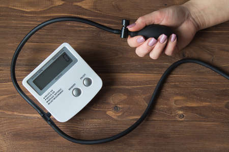 Female hands with pressure meter on a wooden background.の写真素材