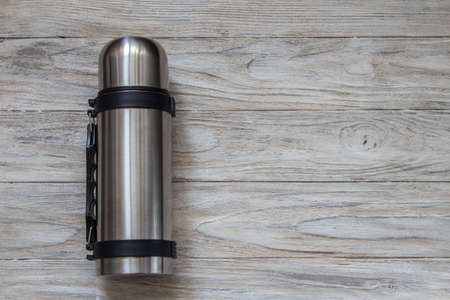 Metal thermos flask on a woden background. Top viewの写真素材