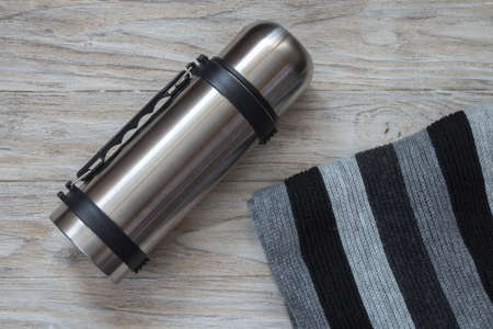 Thermos flask and scarf on a woden background. Top viewの写真素材