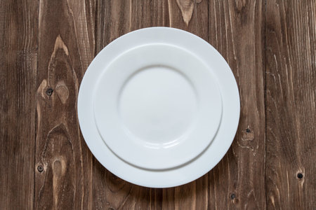 Two white ceramic plate on wooden background