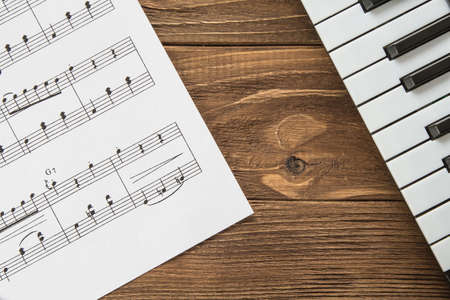 Angled piano keyboard on wooden background with notesの写真素材
