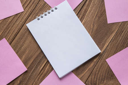 Notebook on wooden background around post-in notesの写真素材