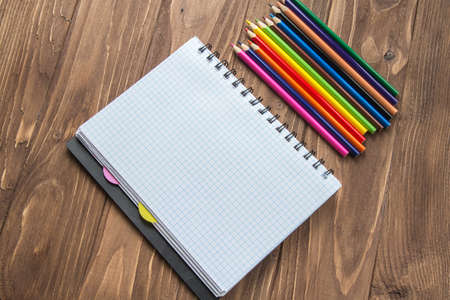 Colored pencils and notepad on wooden backgroundの写真素材