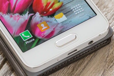 Bottom part of white smartphone with flowers on screen