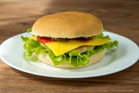 Tasty cheeseburger on white plate on wooden background, closeupの写真素材