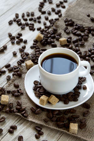 Black coffee in a mug and roasted coffee beans on a wooden background, close-upの写真素材