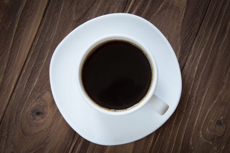 Cup of coffee on brown wooden background top view, close-upの写真素材