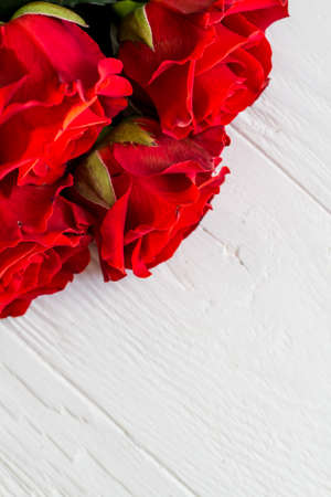 Few red roses in a corner on light wooden background with copyspace, top viewの写真素材