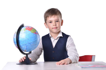 Schoolboy at the desk holding a globe of world, isolated on white backgroundの写真素材