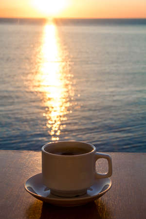White Coffee cup in the morning time with sunrise path on the waterの写真素材