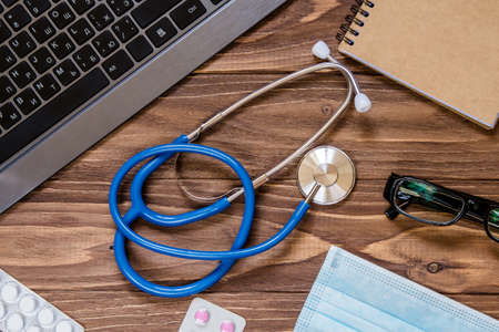 Stethoscope macro view on the wooden desktop. Other medical and office objects on the tableの写真素材