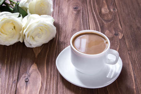 Romantic morning. Coffee cup and three white roses on the wooden table. Romantic luxury breakfastの写真素材