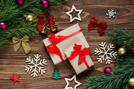 Cute christmas presents on the wooden table surrounded with new years tinsel such as bells, snowflakes, stars, christmas balls, pine tree branches, colorful striped bowsの写真素材