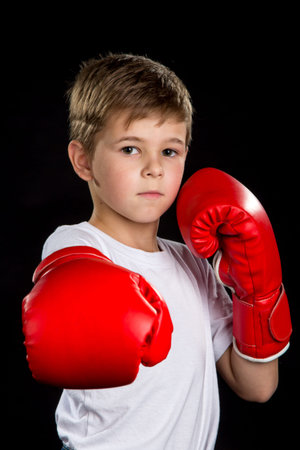 Straight boxing attack kick, demonstration in red boxing gloves. Confident serious boxer portraitの写真素材