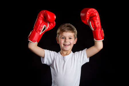 Extremely happy and successful little boxer with both hands up in red boxing glovesの写真素材