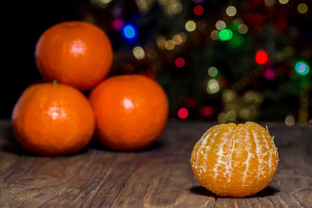 Fresh organic mandarins on a rustic wooden background with one separate peeled tangerineの写真素材