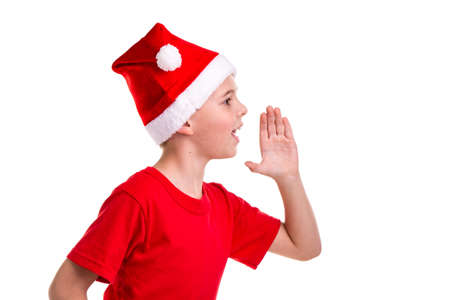 Cute smiling boy, santa hat on his head, with the left hand vertically, calling for. Concept: christmas or Happy New Year holidayの写真素材