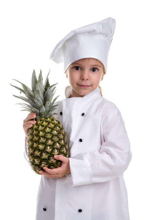 Smiling chef girl in a cook uniform, holding pineapple. Positive human emotion, facial expression feeling, attitudeの写真素材