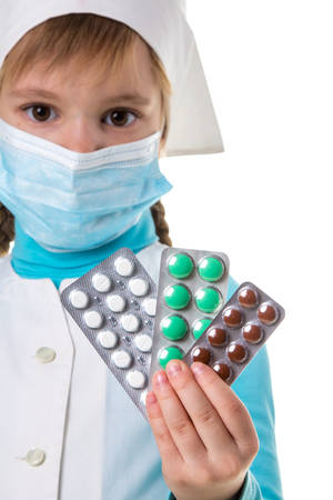 A lot of pills of different color in the female nurse hands. Pills close up. Nurse with medical mask, looking straight at the cameraの写真素材