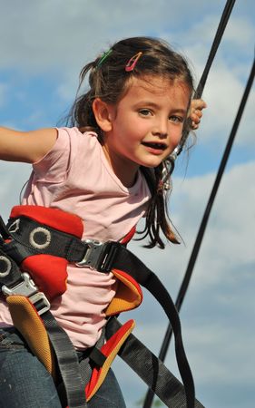 Little girl jumping on the trampoline (bungee jumping).の写真素材